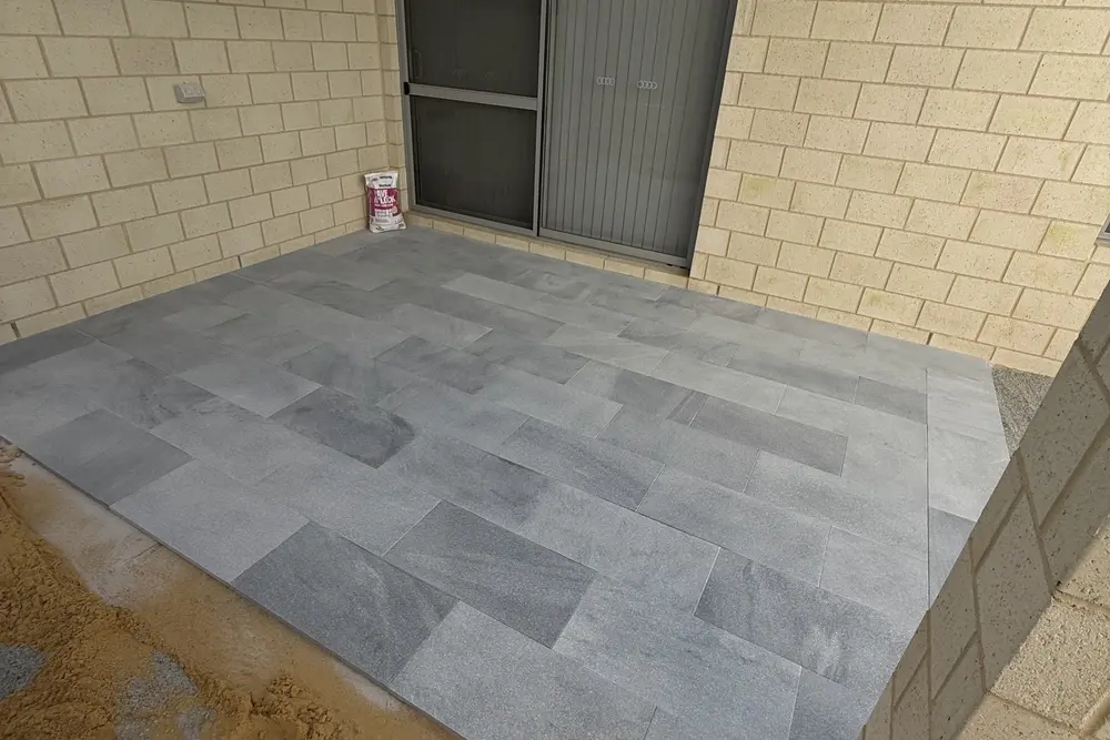 Courtyard paving in grey large format pavers between limestone walls in Perth by IBP Paving